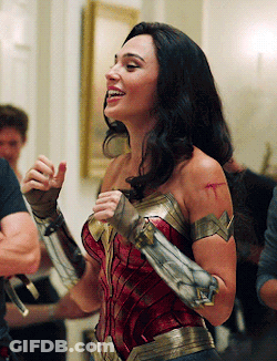 A Woman In A Wonder Woman Costume Is Smiling While Standing In A Room GIF