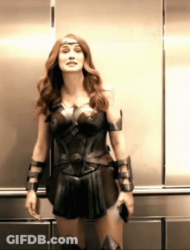 A Woman In A Wonder Woman Costume Is Standing In A Elevator GIF