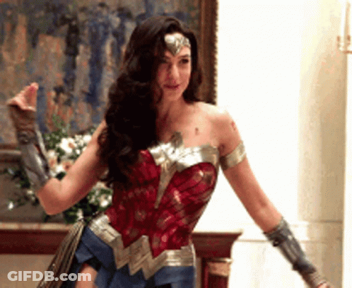 A Woman In A Wonder Woman Costume Is Standing In Front Of A Painting . GIF