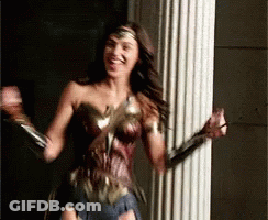 A Woman In A Wonder Woman Costume Is Standing In Front Of A Pillar . GIF