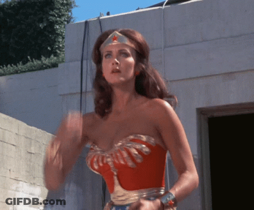 A Woman In A Wonder Woman Costume Is Waving GIF