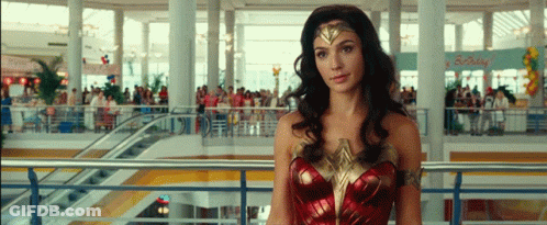 A Woman In A Wonder Woman Costume Stands In A Crowded Mall GIF
