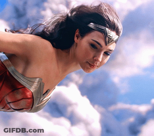 A Woman In A Wonder Woman Outfit Is Flying Through The Air GIF