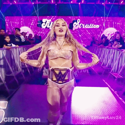 A Woman In A Wrestling Outfit Is Walking Down A Purple Aisle With The Word Stratton Behind Her GIF