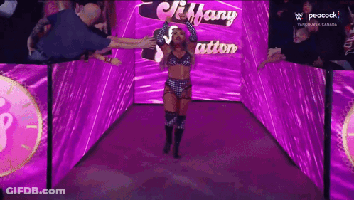 A Woman In A Wrestling Outfit Is Walking Through A Purple Tunnel GIF