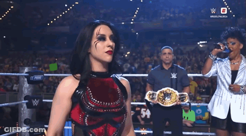 A Woman In A Wrestling Ring Holding A Belt That Says ' W ' On It GIF