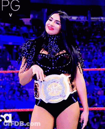 A Woman In A Wrestling Ring Holding A Championship Belt GIF
