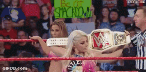 A Woman In A Wrestling Ring Holding A Sign That Says Be At Stackdown . GIF