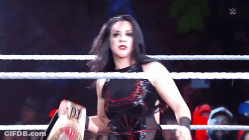 A Woman In A Wrestling Ring Holds A Championship Belt GIF