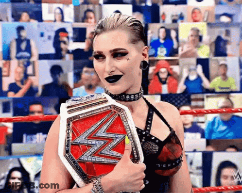 A Woman In A Wrestling Ring Is Holding A Championship Belt . GIF