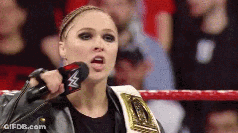 A Woman In A Wrestling Ring Is Holding A Microphone With A W On It GIF