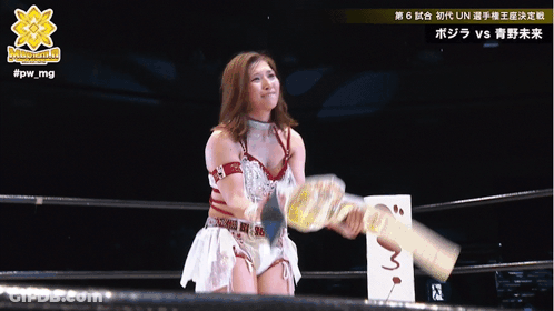 A Woman In A Wrestling Ring Is Holding A Trophy And The Hashtag #Fpw_mg Is Above Her GIF