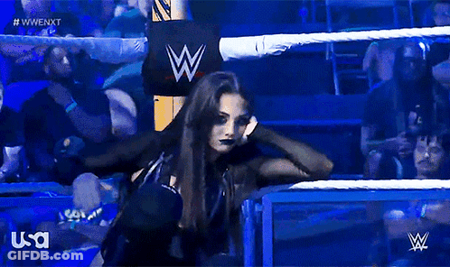 A Woman In A Wrestling Ring With A W Logo In The Background GIF