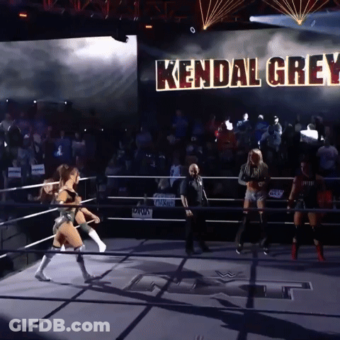 A Woman In A Wrestling Ring With Kendal Grey Written On A Large Screen Behind Her GIF