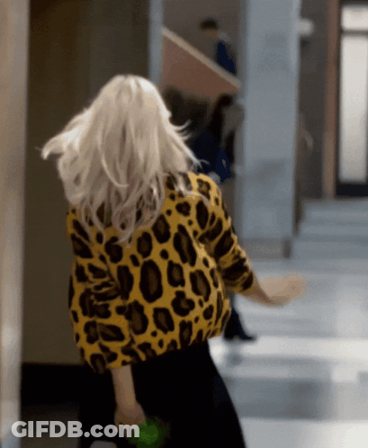 A Woman In A Yellow And Black Leopard Print Sweater GIF