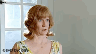 A Woman In A Yellow And White Floral Dress Is Standing In Front Of A Window . GIF