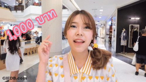A Woman In A Yellow And White Shirt Points To A Sign That Says 1,000 บาท GIF