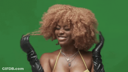 A Woman In A Yellow Bikini And Black Gloves Is Smiling On A Green Background . GIF