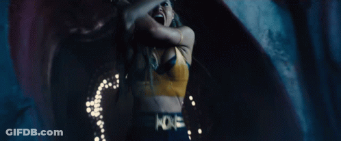 A Woman In A Yellow Bra Is Dancing In A Dark Room With A Blue Background . GIF