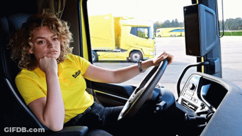 A Woman In A Yellow Daf Shirt Sits In A Truck GIF