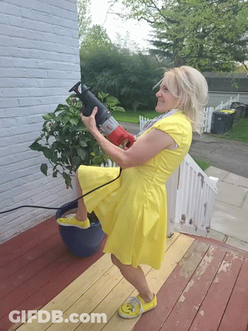A Woman In A Yellow Dress Holds A Red Saw GIF