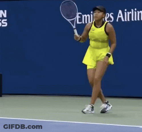 A Woman In A Yellow Dress Is Holding A Tennis Racquet GIF