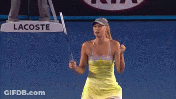 A Woman In A Yellow Dress Is Holding A Tennis Racquet On A Court . GIF