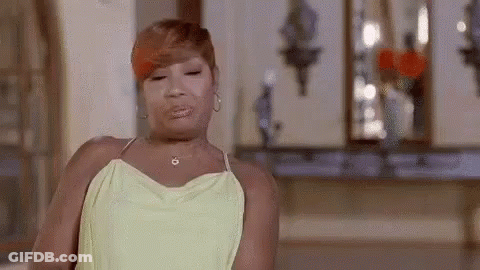 A Woman In A Yellow Dress Is Making A Funny Face In A Room . GIF