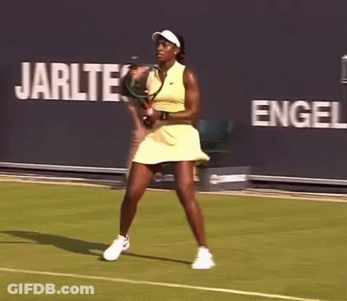 A Woman In A Yellow Dress Is Playing Tennis On A Court GIF