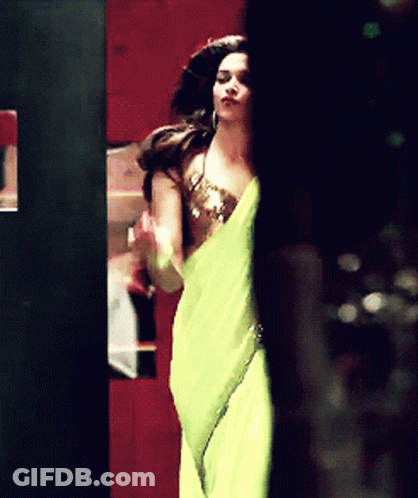 A Woman In A Yellow Dress Is Standing In A Dark Room GIF