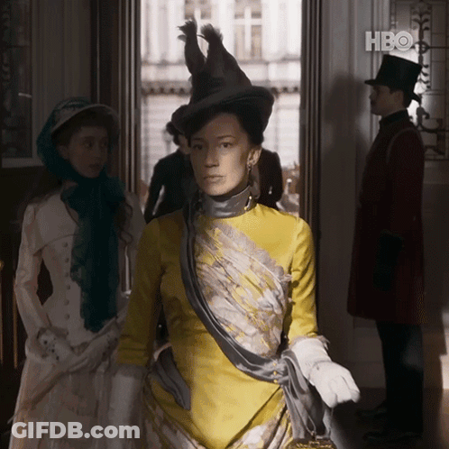 A Woman In A Yellow Dress Is Standing In A Doorway With A Hbo Logo In The Background GIF