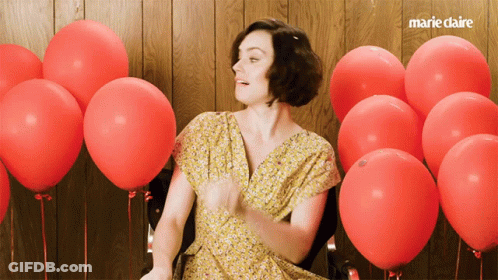 A Woman In A Yellow Dress Is Surrounded By Red Balloons And The Words Marie Claire Are On The Bottom GIF