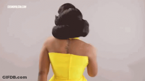 A Woman In A Yellow Dress With A Tattoo On Her Back Is Standing With Her Back To The Camera . GIF