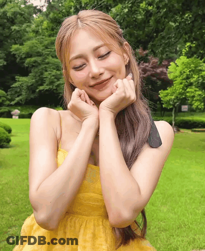 A Woman In A Yellow Dress With Her Hands On Her Face GIF