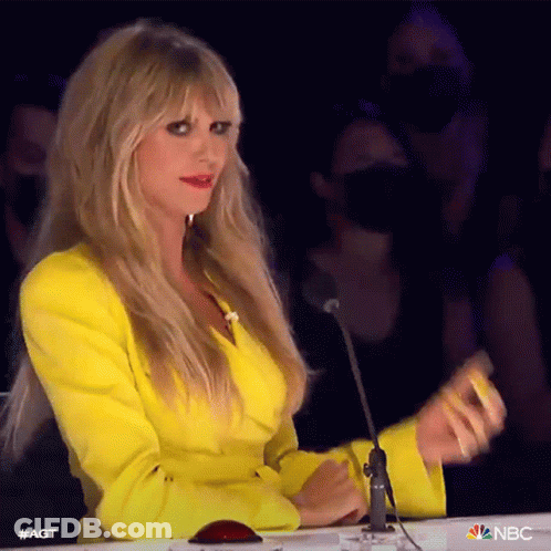A Woman In A Yellow Jacket Is Sitting At A Table With A Microphone In Front Of Her . GIF