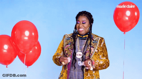 A Woman In A Yellow Jacket Is Surrounded By Red Balloons And Has A Cinc Necklace Around Her Neck GIF