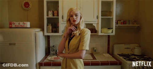 A Woman In A Yellow Jacket Stands In A Kitchen With A Netflix Logo On The Bottom GIF