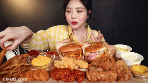 A Woman In A Yellow Plaid Shirt Is Eating A Lot Of Fried Food GIF