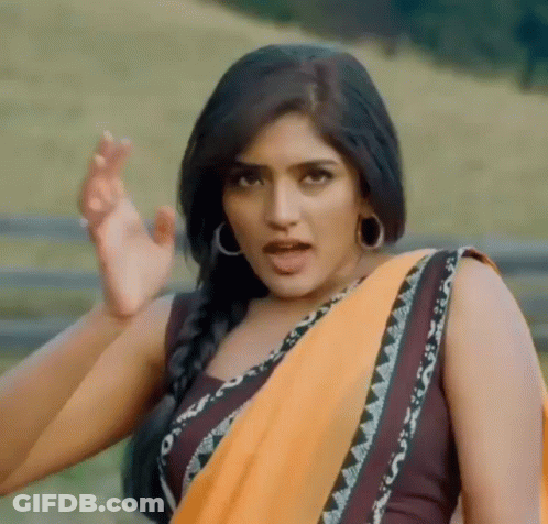 A Woman In A Yellow Saree Is Making A Funny Face While Standing In A Field . GIF