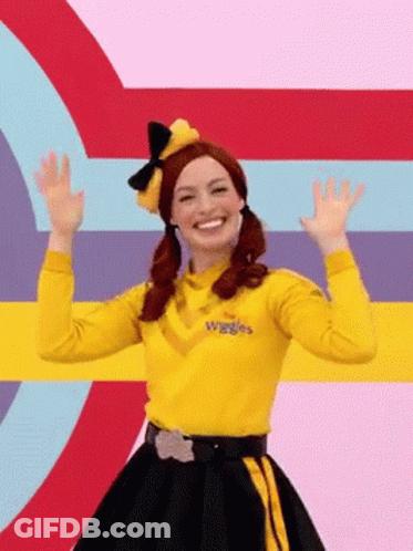 A Woman In A Yellow Shirt And Black Skirt Is Standing In Front Of A Colorful Background . GIF