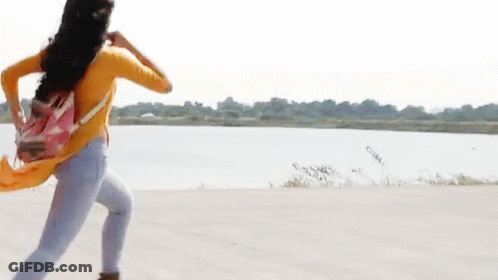A Woman In A Yellow Shirt And Blue Jeans Is Running With A Pink Backpack GIF