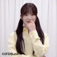 A Woman In A Yellow Shirt Is Covering Her Mouth With Her Hand And Smiling . GIF