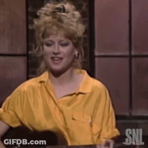 A Woman In A Yellow Shirt Is Sitting At A Table With A Glass Of Wine . GIF