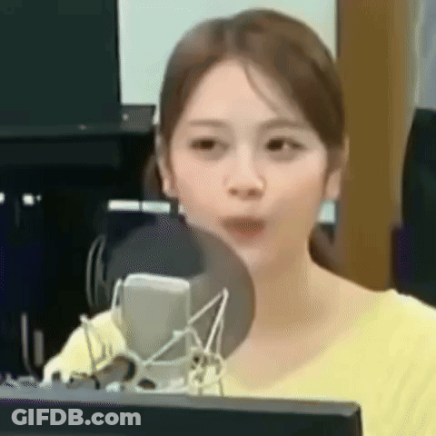 A Woman In A Yellow Shirt Is Sitting In Front Of A Microphone . GIF