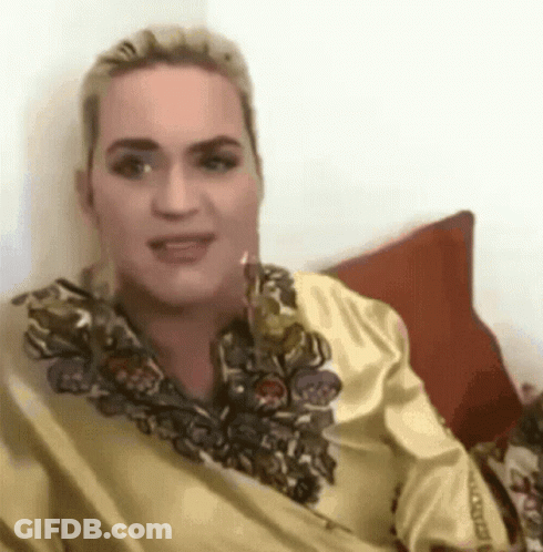 A Woman In A Yellow Shirt Is Sitting On A Couch With A Red Pillow . GIF