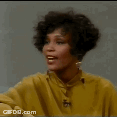 A Woman In A Yellow Shirt Is Smiling And Laughing . GIF