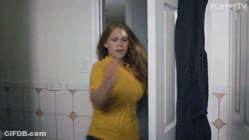 A Woman In A Yellow Shirt Is Standing In A Doorway With #Crypttv Written On The Bottom Right GIF