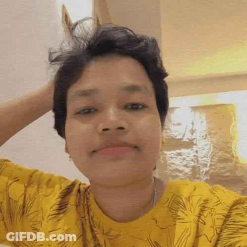 A Woman In A Yellow Shirt Is Taking A Picture GIF