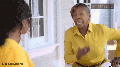 A Woman In A Yellow Shirt Is Talking To Another Woman In Front Of A Window . GIF