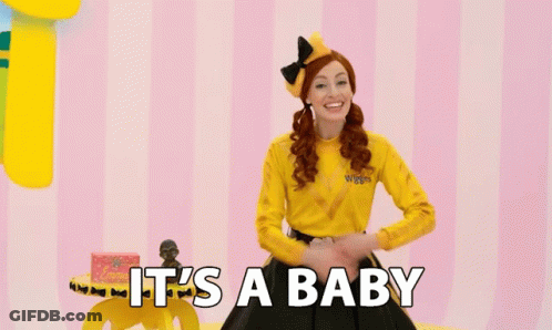A Woman In A Yellow Shirt With The Words It 'S A Baby On The Bottom GIF